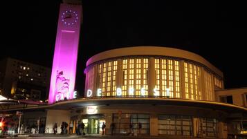 Un bâtiment doté d’un grand beffroi et dont la façade est illuminée, avec le nom « DEBRES » inscrit dessus.