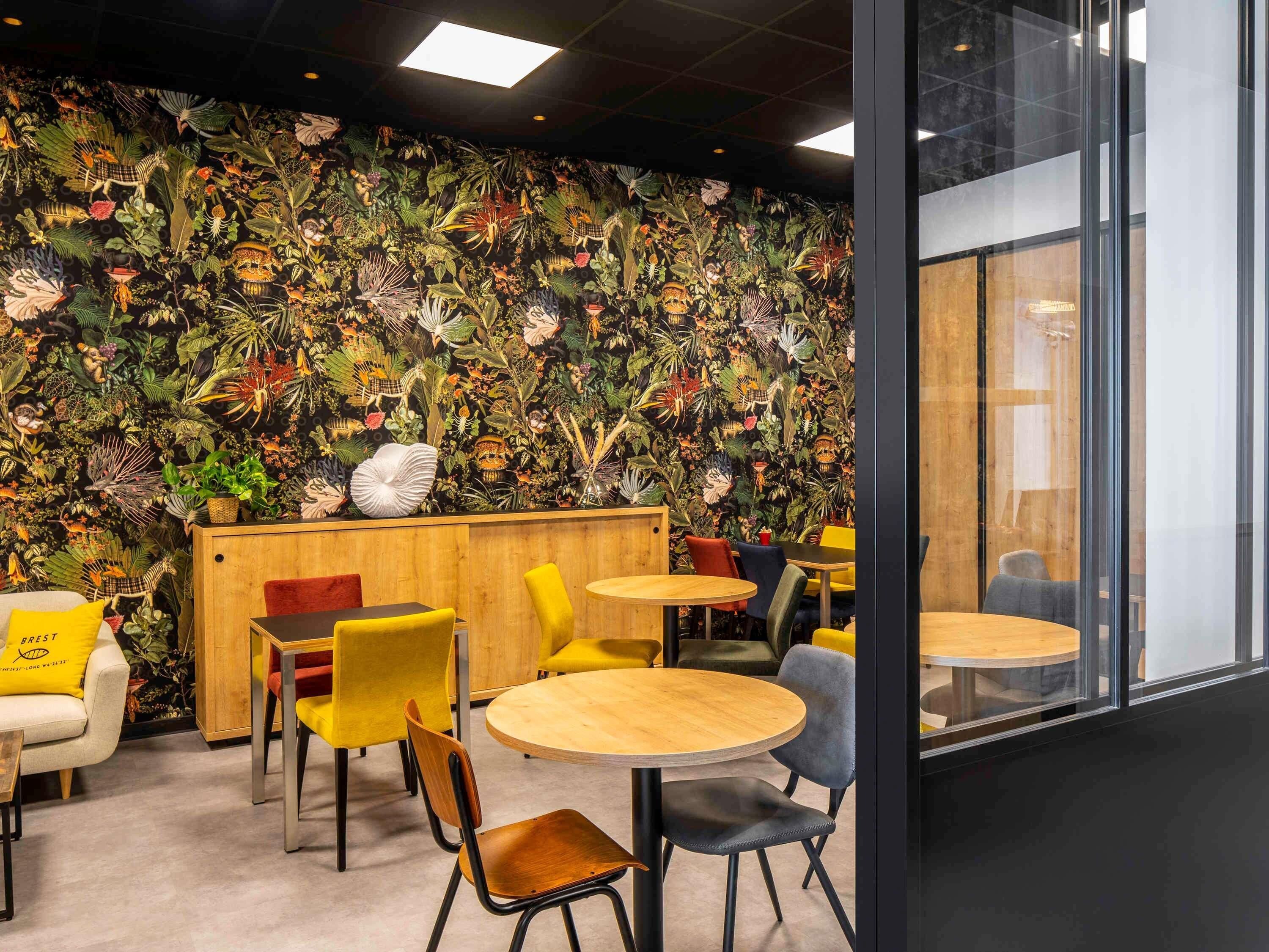 A modern interior with a vibrant tropical-themed wall, wooden furniture, and a glass partition.
