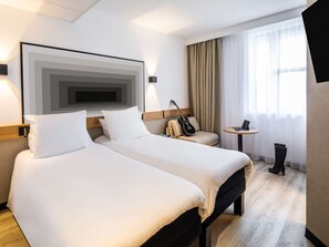 Relax in a serene space with two single beds, a work area, and a large window.