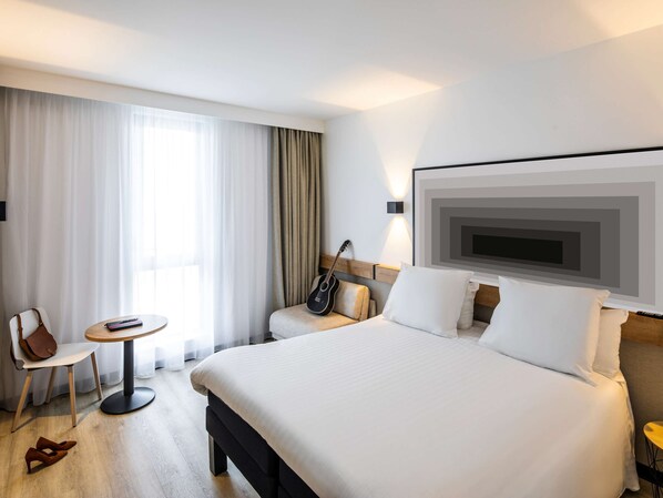 Relax in a stylish room with a large bed, wall-mounted TV, and a small table with a chair.