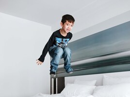 Niño saltando en una litera en una habitación con paredes blancas y un diseño moderno y sencillo.