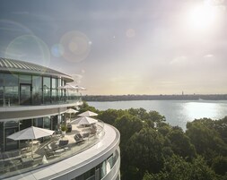 Ein modernes Gebäude mit Glasfassade, Außenbereich und Blick auf ein Gewässer.