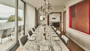 A dining area with a long table set for six, large windows, and a view of the outdoors.