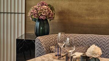 A dining area with a marble table, patterned cushions, and a vase of flowers.