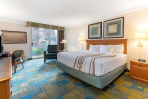 A hotel room with a large bed, a desk, a chair, and a view of the outdoors. - La Quinta Inn & Suites by Wyndham Redding (Redding)
