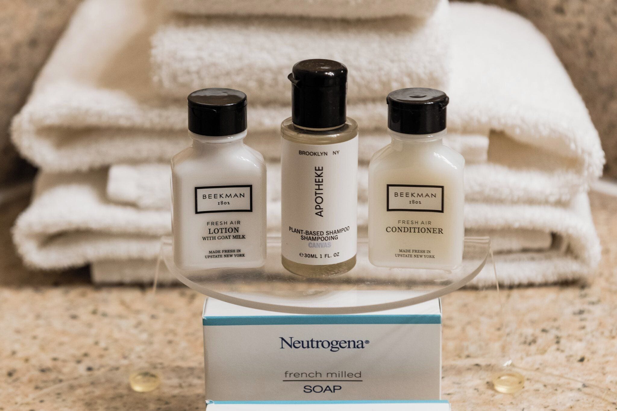 Trois flacons de produits de soins pour la peau sont présentés sur un présentoir, avec un pain de savon Neutrogena placé en dessous.
