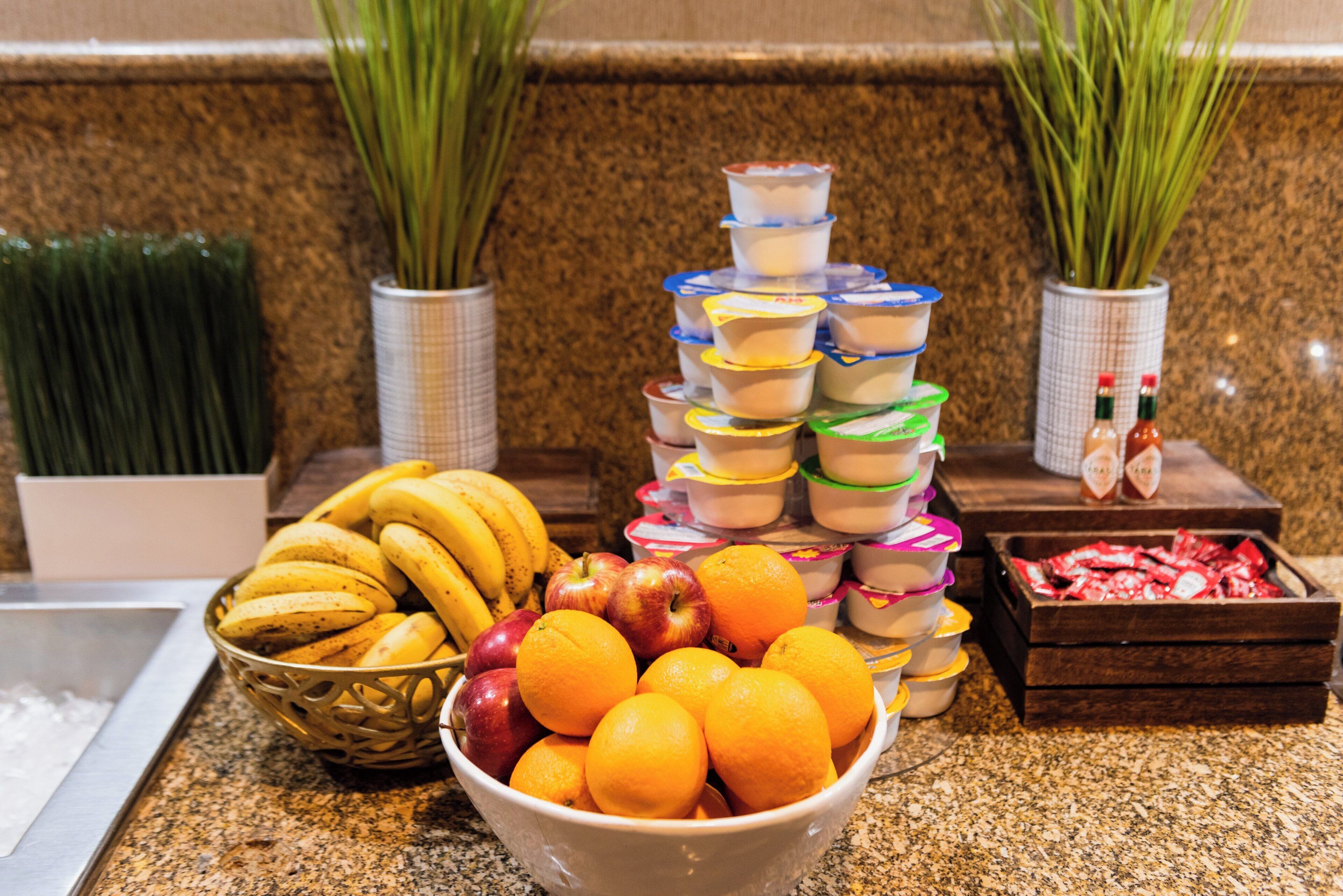 A buffet table with a variety of fruits and yogurt containers.