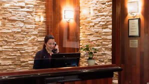 A reception desk with a stone wall backdrop, a framed certificate, and a potted plant.