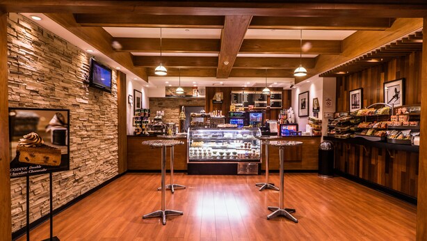 Une boulangerie avec un mur en pierre, un plafond en bois et une vitrine remplie de produits de boulangerie.