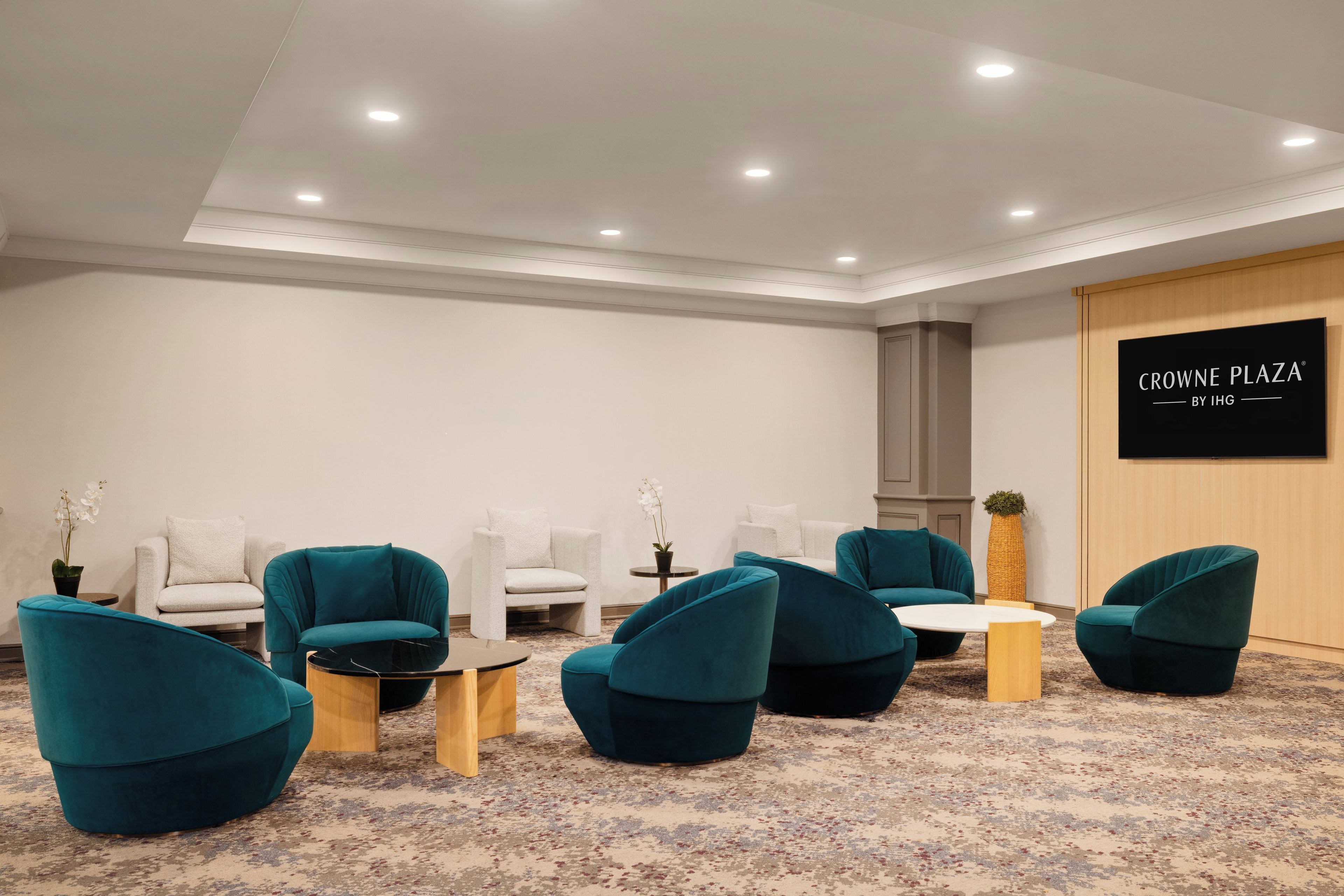 Un salón de conferencias con sillas color turquesa, un sofá blanco y una mesa redonda.