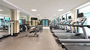 Une salle de sport équipée de tapis de course, d’haltères et d’appareils de musculation.