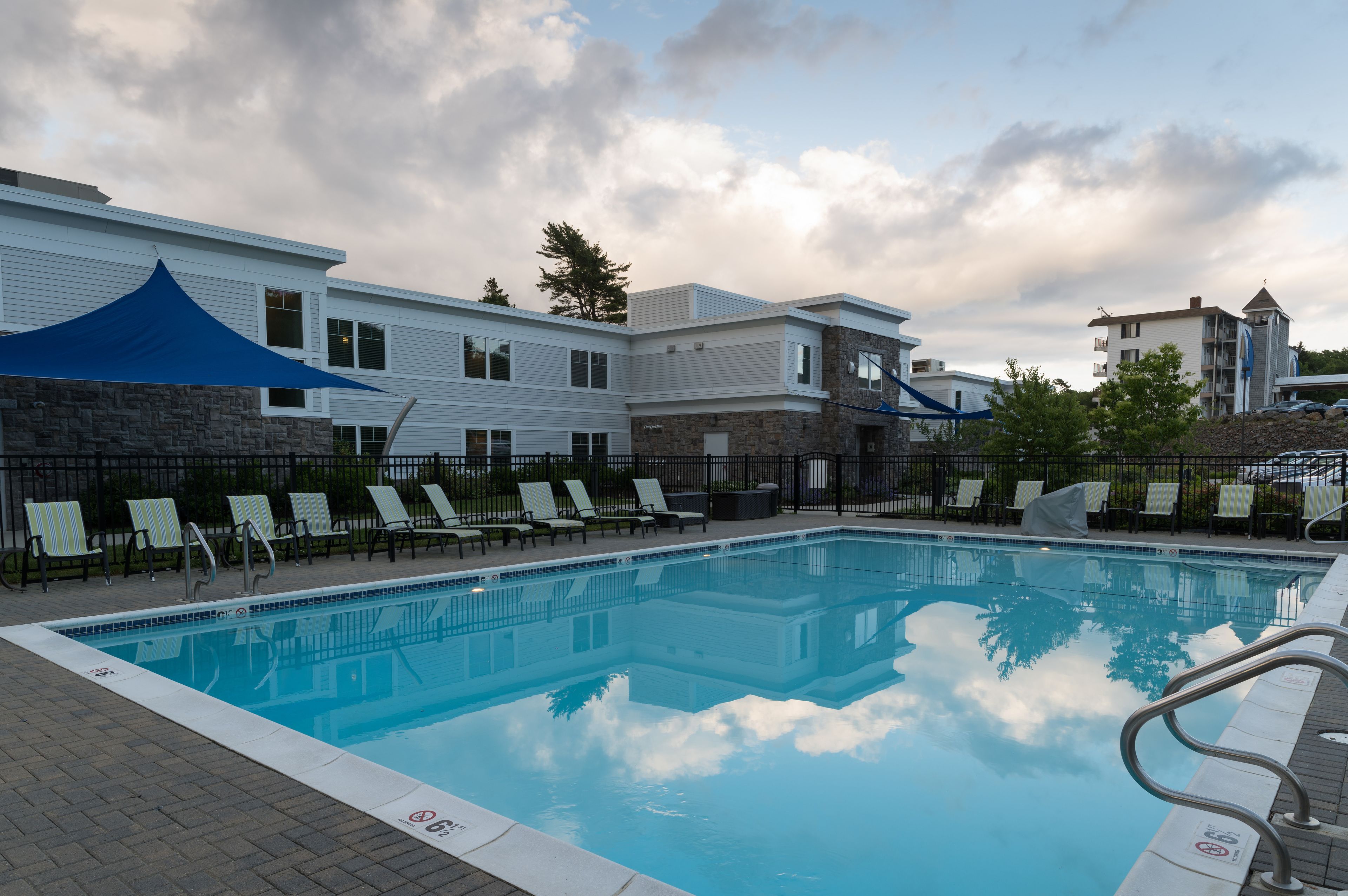 A swimming pool with lounge chairs and a stone wall.