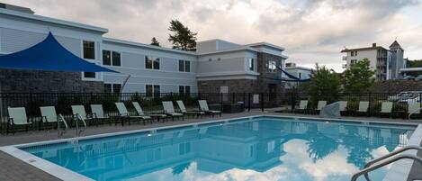 A swimming pool with lounge chairs and a stone wall.