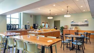 A spacious dining area with high ceilings, pendant lighting, and a large window providing natural light.