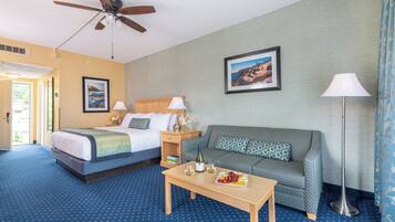 A hotel room with a bed, a sofa, a coffee table, and a ceiling fan.