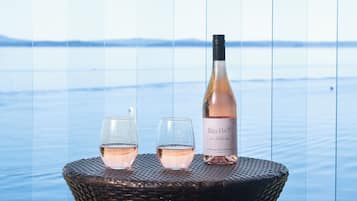 A wicker table with two glasses of rosé wine and a bottle of Billa-Haut wine.