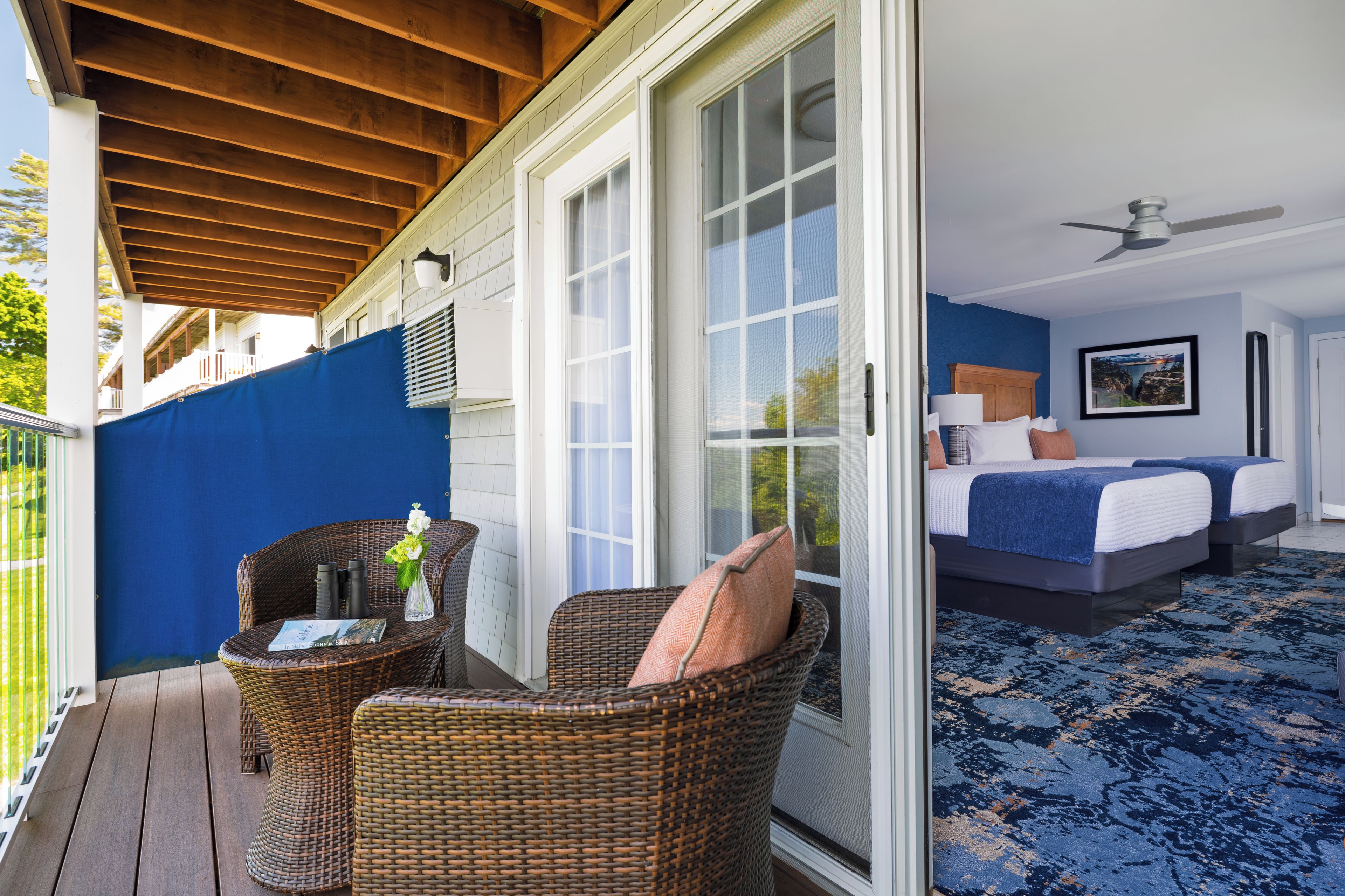 Une chambre avec un lit, un ventilateur de plafond et une vue sur l’extérieur, accessible par une porte-fenêtre coulissante.