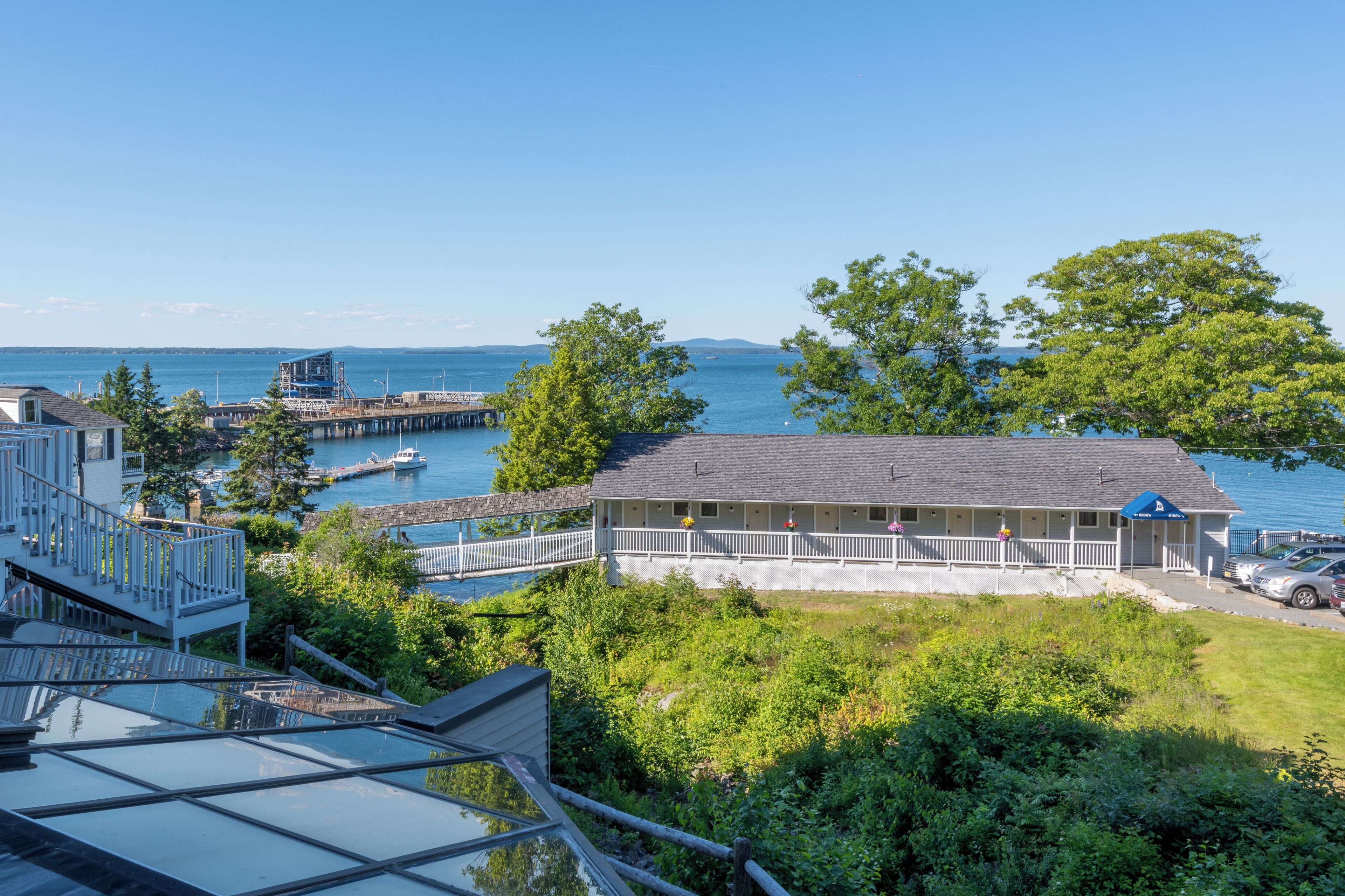 A coastal property with a large house overlooking the sea, a dock, and a swimming pool.