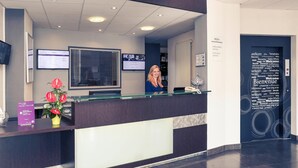 A reception desk with a computer monitor, a glass partition, and a welcome sign. - Mercure Saint Lo Centre (Saint-Lo)