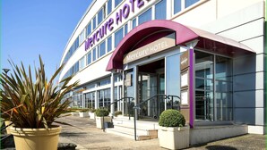 A Mercure Hotel with a modern facade, large windows, and a prominent entrance with a purple awning. - Mercure Saint Lo Centre (Saint-Lo)