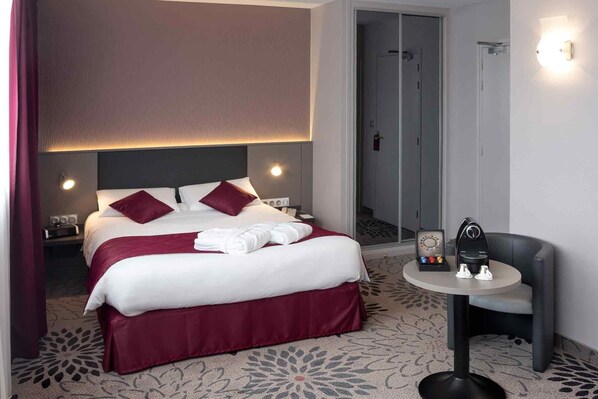 A hotel room with a bed, a round table with a chair, and a door leading to a bathroom.