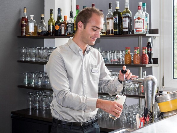 A bartender preparing a drink with a shaker and a bottle of Heineken.
