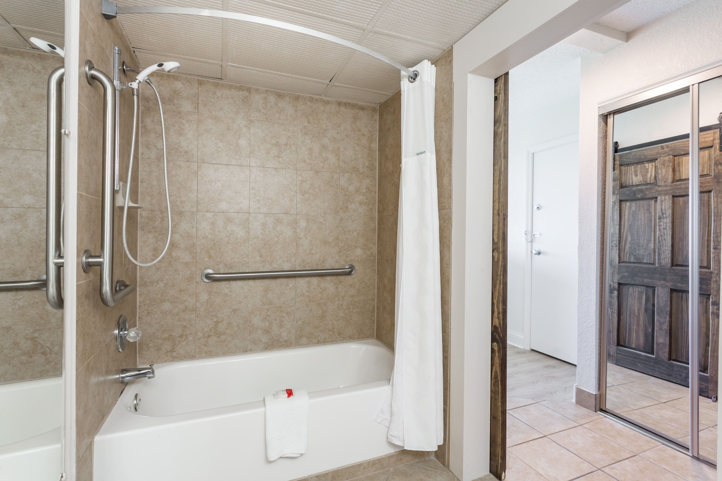 A bathroom with a bathtub, shower, and grab bars.