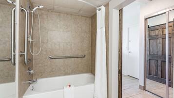 A bathroom with a bathtub, shower, and grab bars.