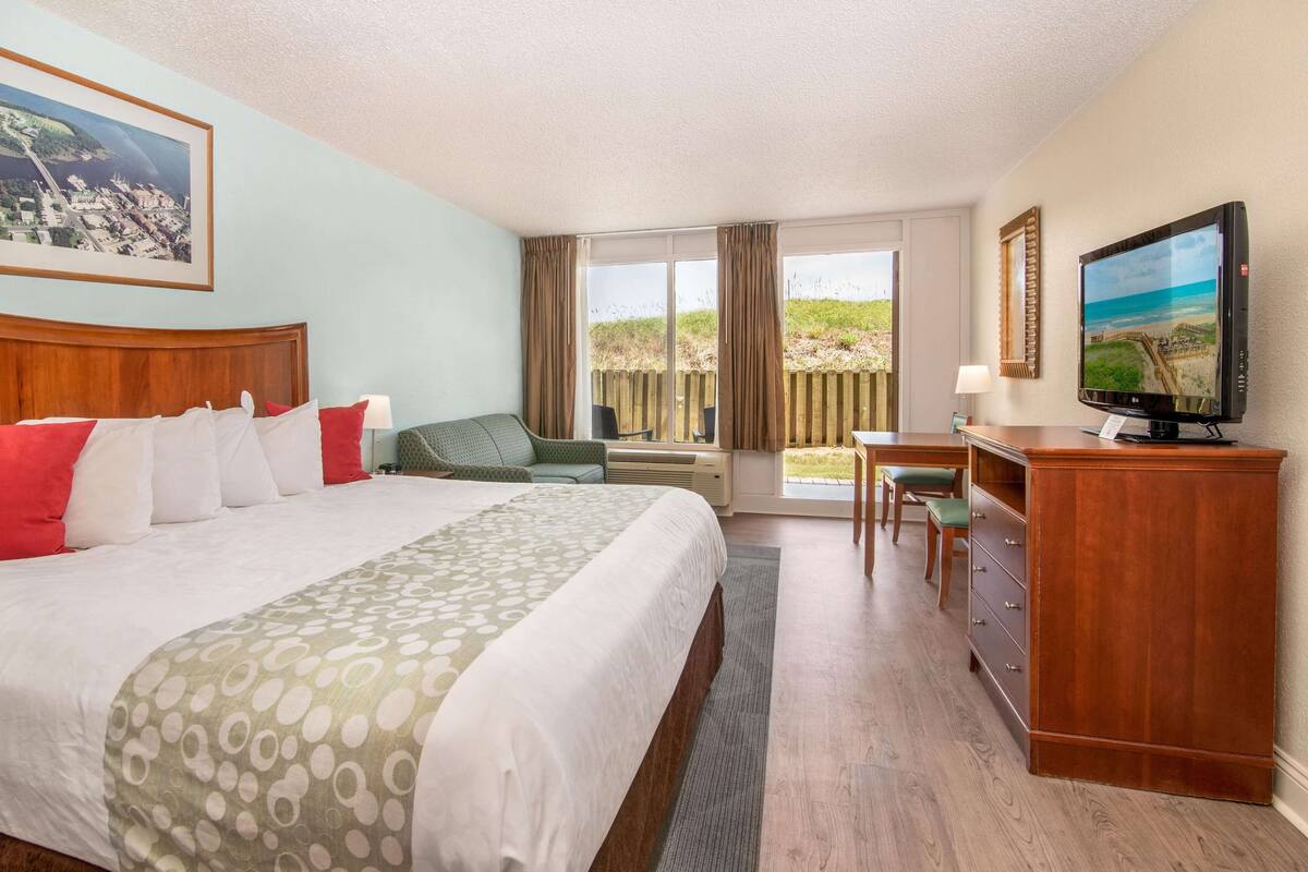 Een hotelkamer met een groot bed, een bureau, een televisie en een raam met uitzicht op de omgeving.