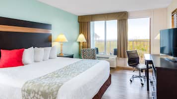 Een hotelkamer met een bed, een bureau met televisie, een stoel, een lamp en een raam met gordijnen.