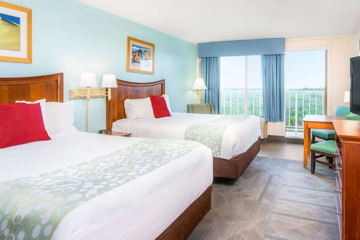 Een hotelkamer met twee bedden, een bureau en een televisie.
