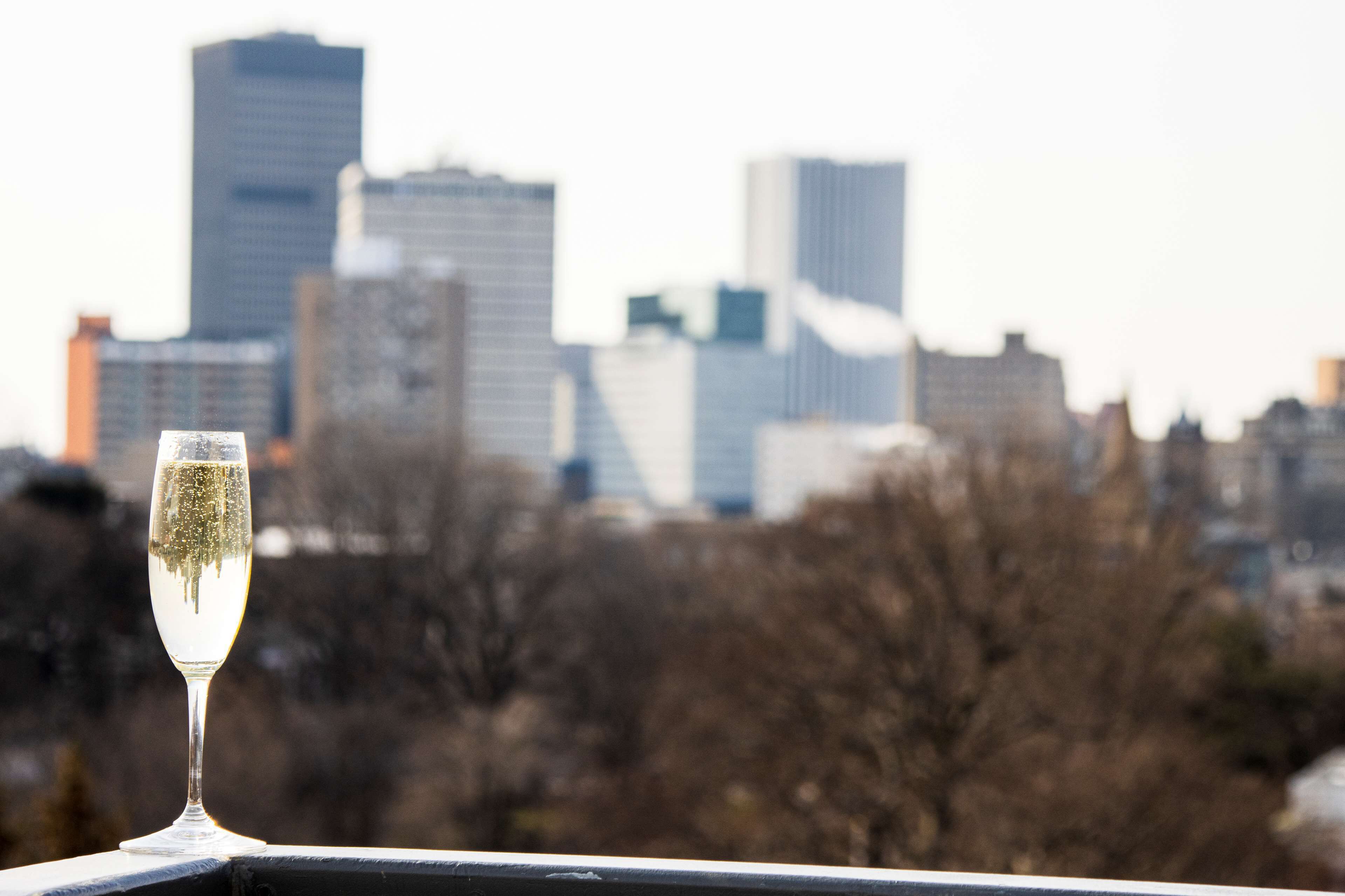 Un verre de champagne sur un balcon, avec la silhouette de la ville en arrière-plan.
