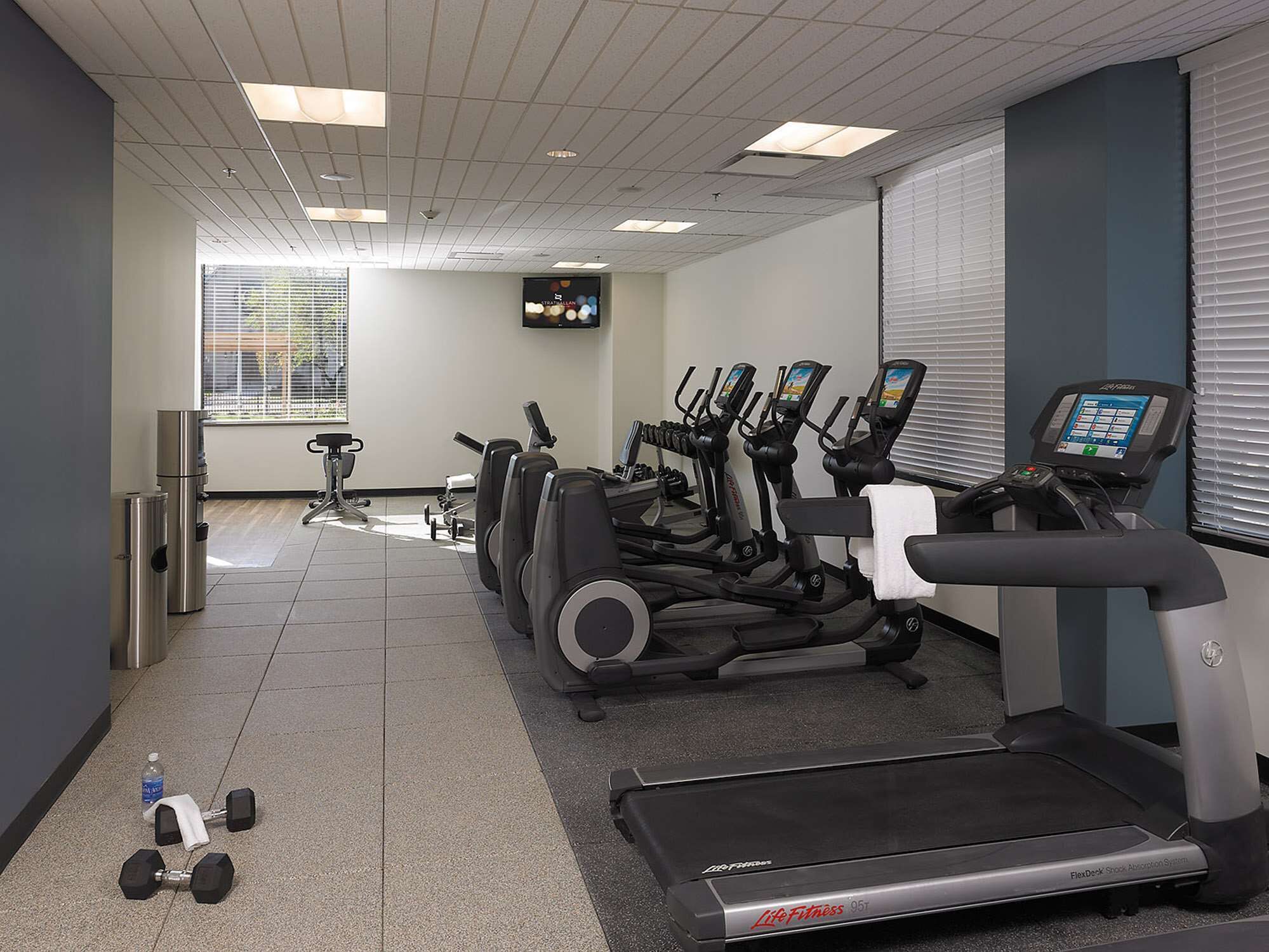 Un gimnasio con cintas de correr, elípticas y mancuernas.