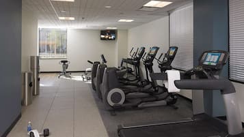 Un gimnasio con cintas de correr, elípticas y mancuernas.
