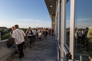 Une terrasse extérieure avec des tables et des chaises, offrant une vue sur le paysage urbain.