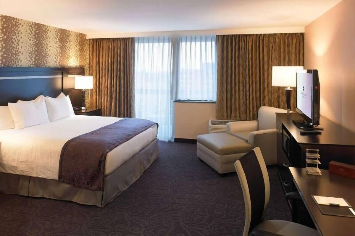 Una habitación de hotel con una cama grande, un escritorio con ordenador, una silla y un televisor.