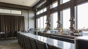 A bar area with a long counter, multiple chairs, and a view through large windows. - The Strathallan Rochester Hotel & Spa, Tapestry by Hilton (Rochester)