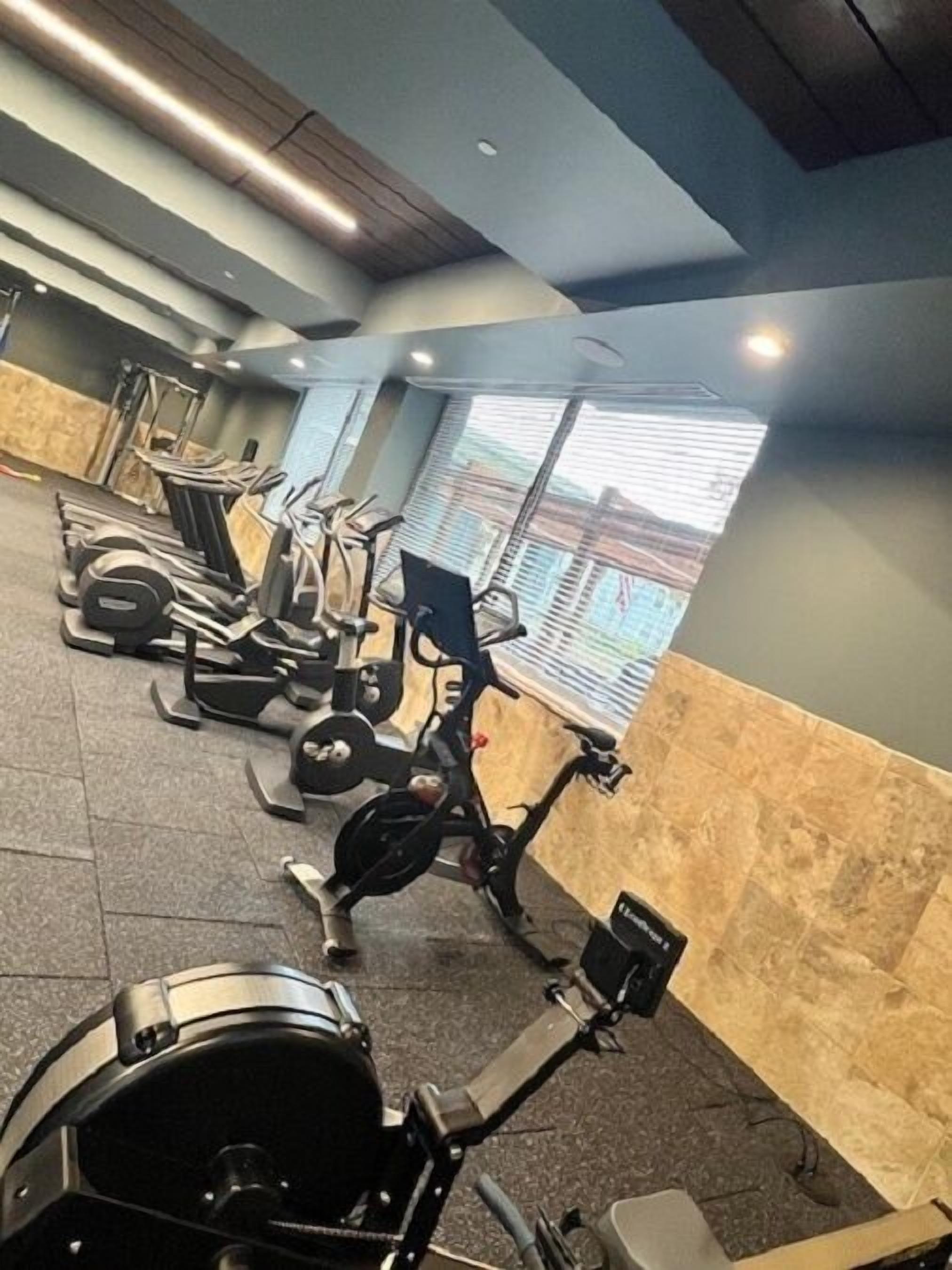 Une salle de sport équipée de divers appareils d’exercice, notamment des tapis de course, des vélos d’appartement et des appareils de musculation.