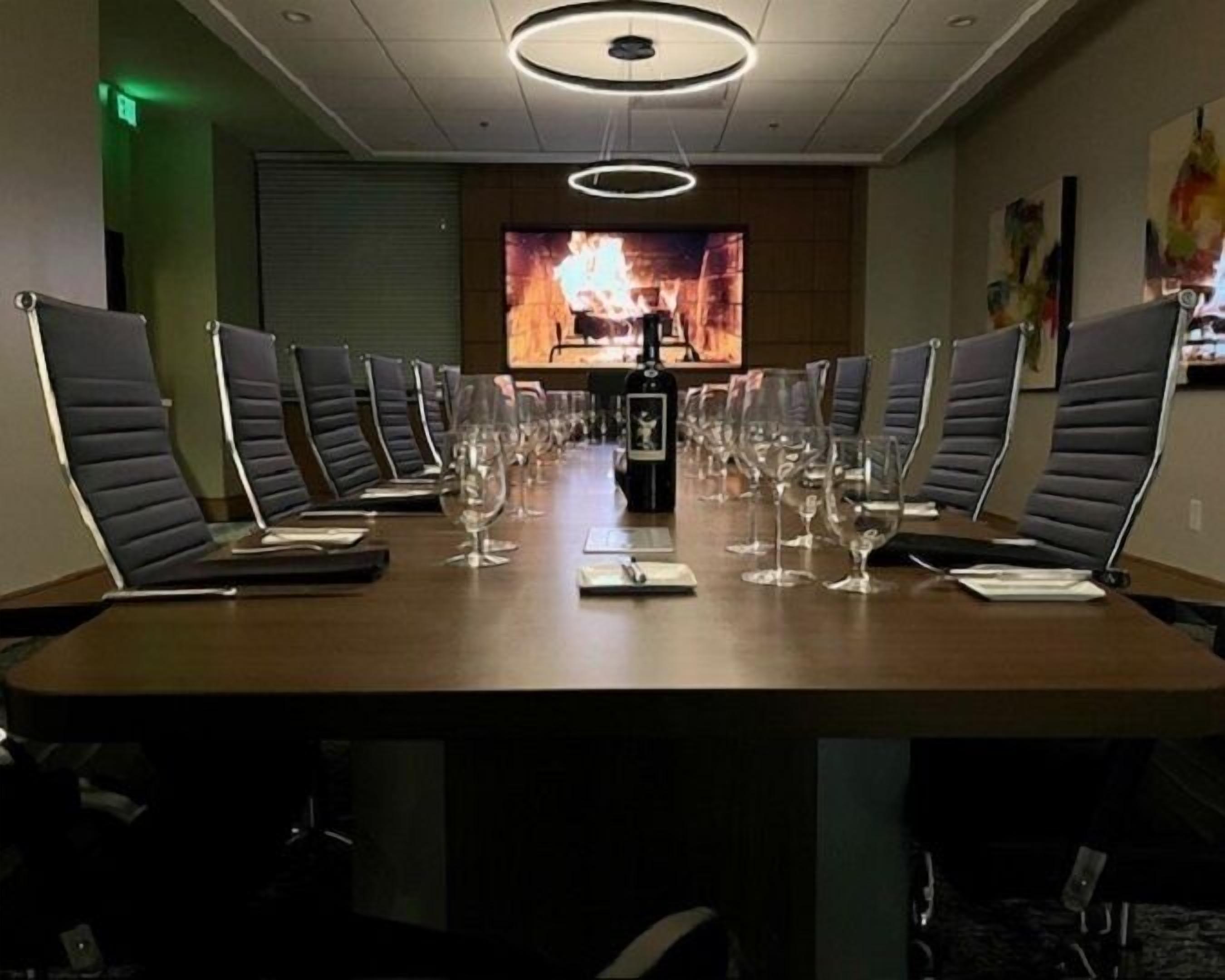 A conference room with a long table, multiple chairs, and empty wine glasses.
