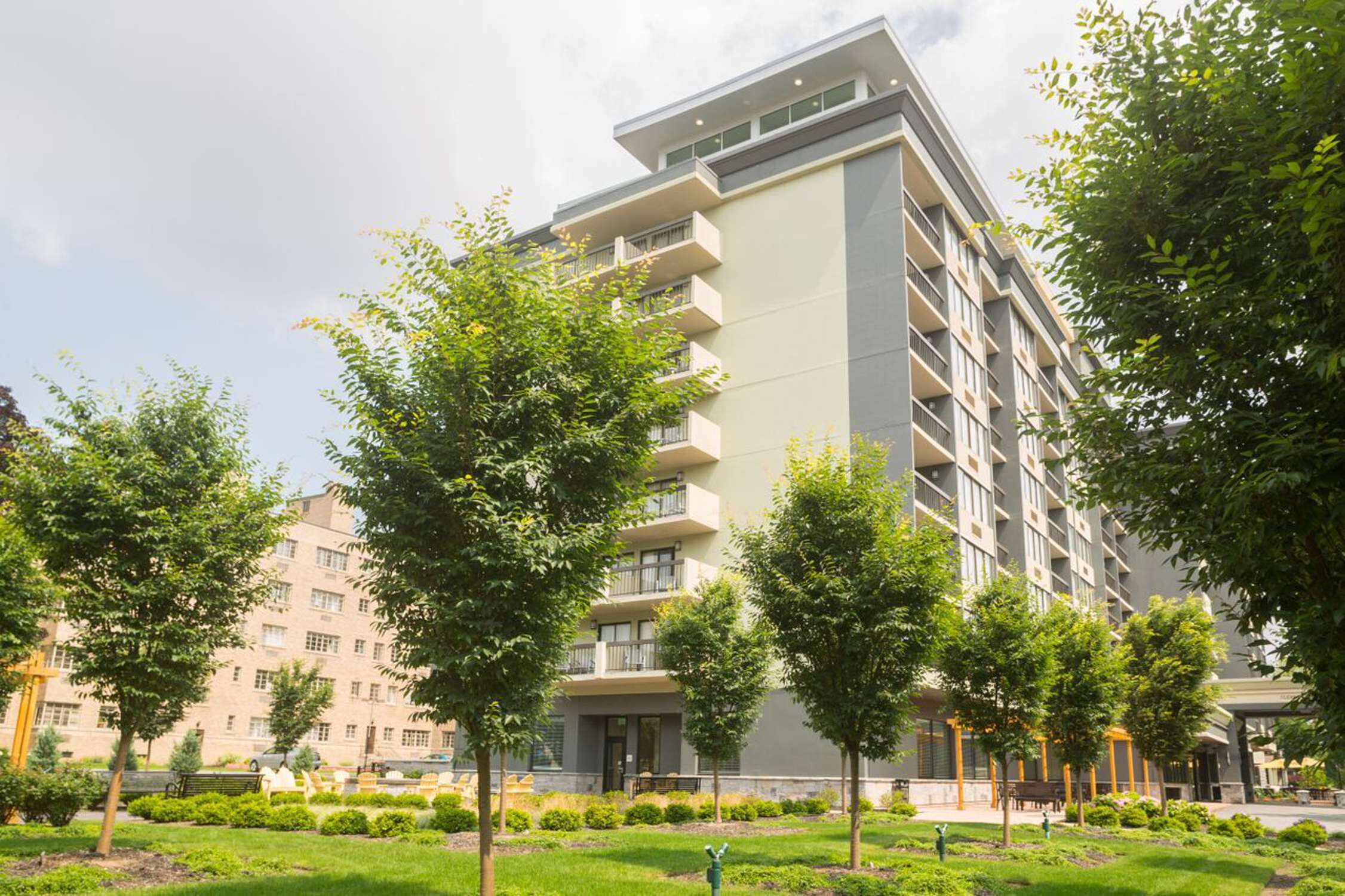 A multi-story hotel with balconies, surrounded by well-maintained greenery and a paved walkway.