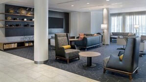 Un lobby moderno con un sofá, sillones, una mesa de centro y una estantería.