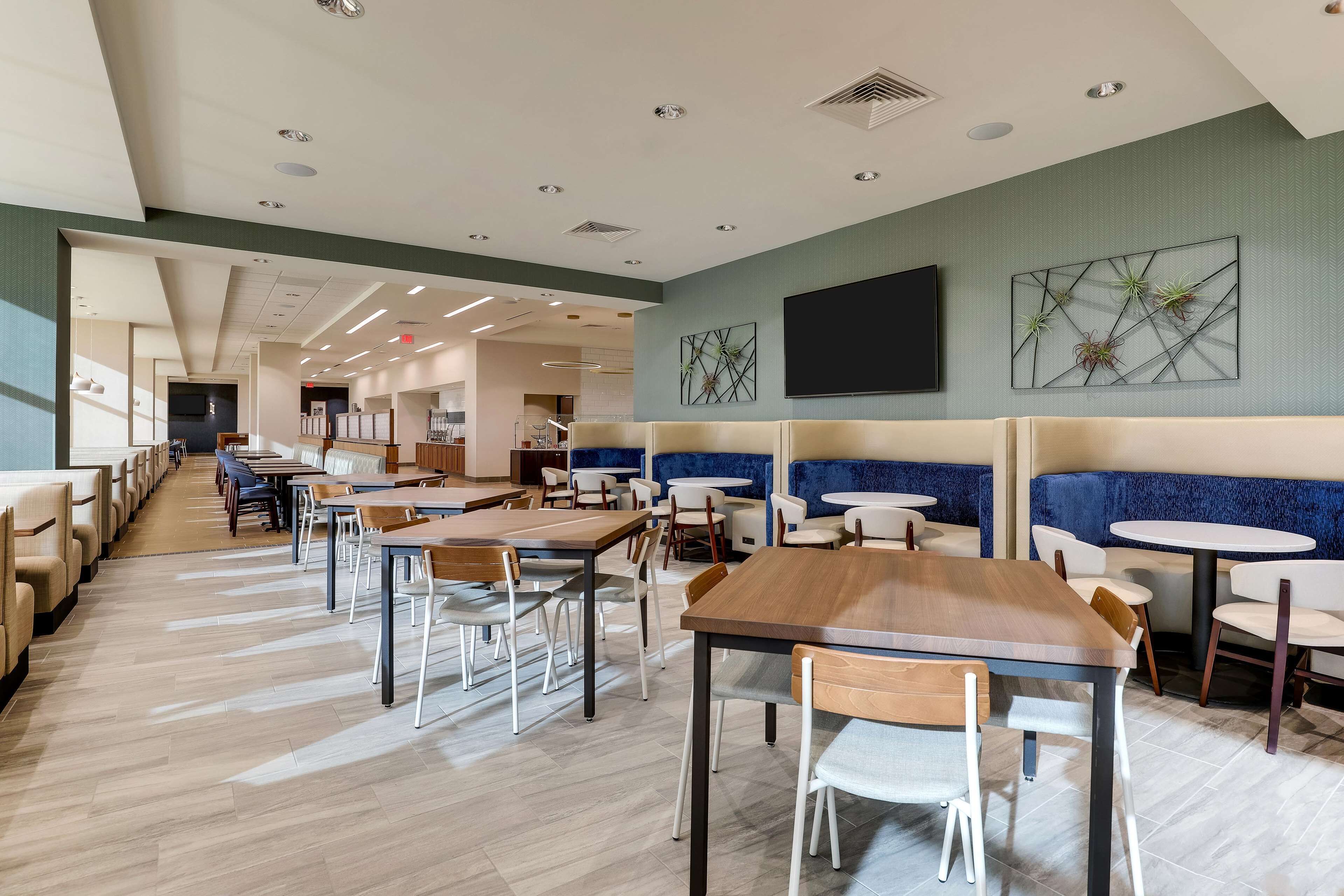 A spacious restaurant with high ceilings, modern lighting, and a mix of seating options including booths and tables.