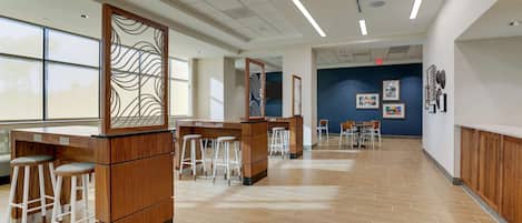 A spacious indoor area with multiple wooden bar stools, a counter, and a seating area with tables and chairs.