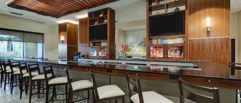 Uma área de bar com painéis de madeira, banquetas e balcão com diversos itens.