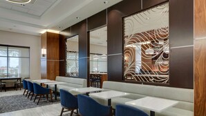 A modern hotel lobby with seating areas, tables, and decorative wall panels. - Drury Plaza Hotel Orlando - Disney Springs Area (Lake Buena Vista)