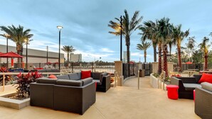 An outdoor patio area with wicker furniture, red accents, and palm trees. - Drury Plaza Hotel Orlando - Disney Springs Area (Lake Buena Vista)
