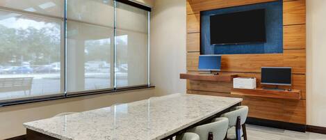 A conference room with a large table, chairs, a TV, and a printer.