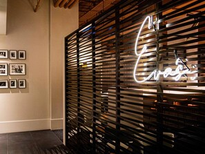 A modern interior with a wooden slatted partition, a neon sign, and framed pictures on the wall. - Pullman Melbourne City Centre (Melbourne)