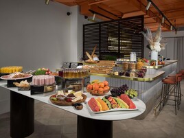 A buffet with various food items and beverages, a bar area with stools, and a modern kitchen in the background.