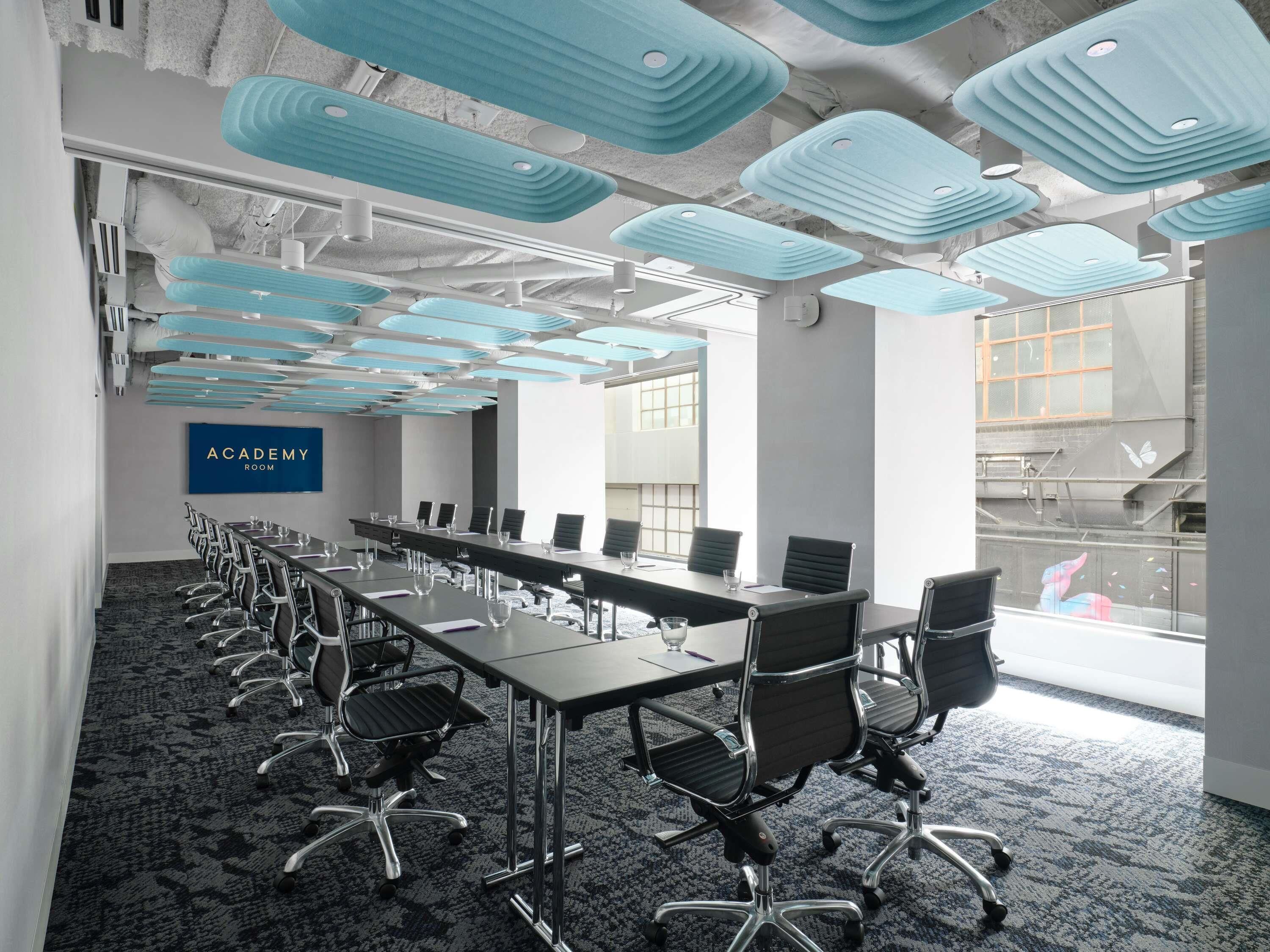 A conference room with a long table, chairs, and a sign reading 'ACADEMY ROOM'.
